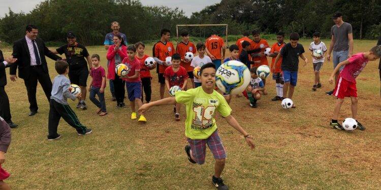 Meninos que treinam futebol em campinhos de bairro ganham bolas novas para treinar no contraturno escolar